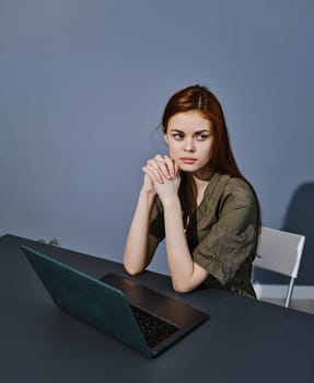 sad redhead woman sitting at a laptop in the office. High quality photo