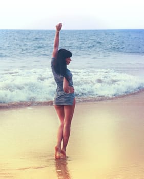 Young girl walking on the beach, holding her hands up. young woman having fun on the ocean coast. Vacation. Sunny beach. High quality photo