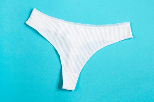 White panties clothes on sky blue background, top view. Bikini, thong everyday. High quality photo