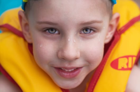 handsome boy in a life jacket laughs. Child with drops on his face. Bathing vest. Vacation concept. water safety. means of protection. High quality photo