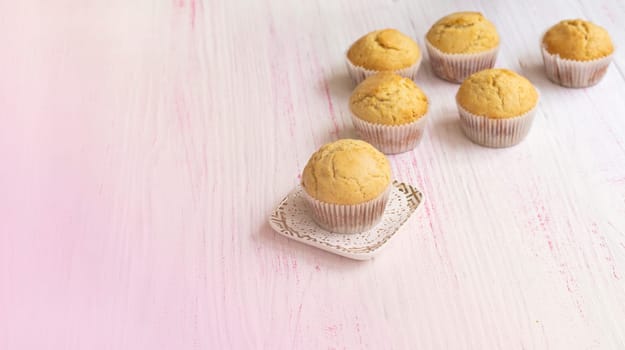 homemade vanilla muffins on a light background. Selective focus. Small muffins in paper tins cool down on the table. Freshly baked muffins. homemade cakes, fresh cupcakes. High quality photo
