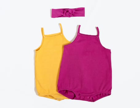 Summer outfit. Baby vest bodysuit yellow and pink color with head accessories. Top view, flat lay on white