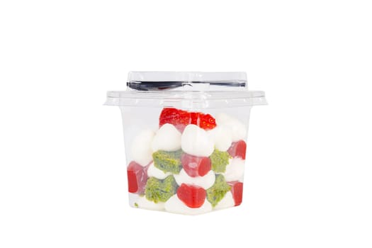 Dessert of cream, spinach, jam and strawberries in a plastic glass on a white background. High quality photo