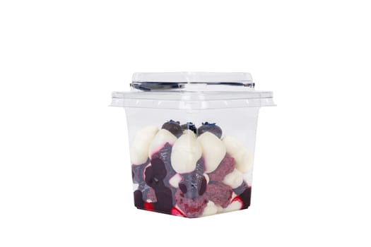 Dessert of cream, jam and blueberries in a plastic glass on a white background. High quality photo