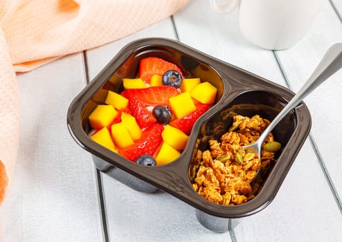 Dessert of cream, mango, strawberries and muesli on a wooden background. High quality photo