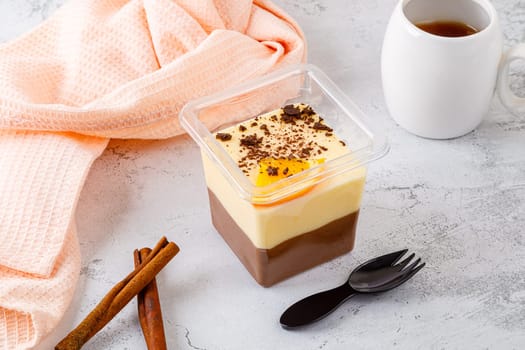 Tiramisu dessert in a plastic box with a fork on a concrete background. High quality photo