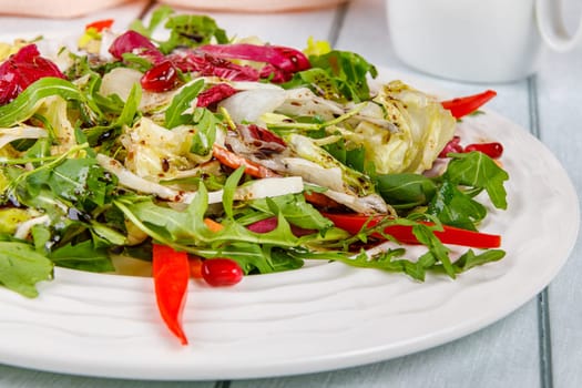 Fresh salad of cabbage, herbs, peppers, carrots and pomegranate seeds in a white plate. High quality photo