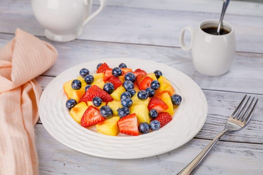 Fruit salad with pineapple, strawberries and blueberries on a white plate. High quality photo
