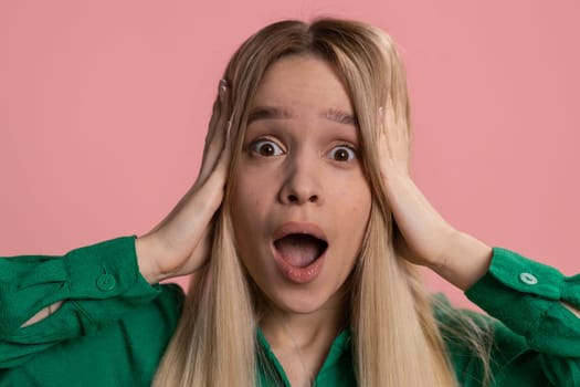 Oh my God, Wow. Excited amazed winner woman surprise looking at camera with big eyes, shocked by sudden victory. Sincere confused shocked young caucasian girl isolated alone on pink studio background