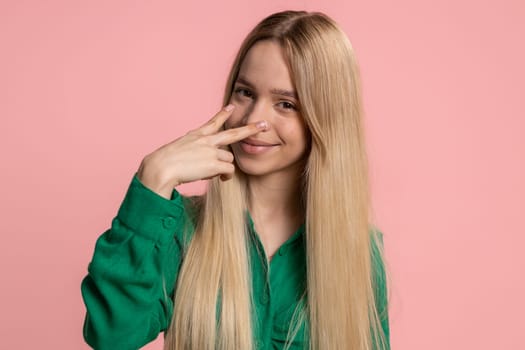 I am watching you. Young confident caucasian woman pointing at her eyes and camera, show I am watching you gesture, spying on someone. Pretty teenager girl isolated alone on pink studio background