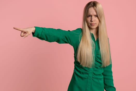 Get out of here. You are fired. Young irritated caucasian woman pointing finger away asking to leave him alone, strict boss firing, conflict. Pretty girl isolated on studio pink background indoors