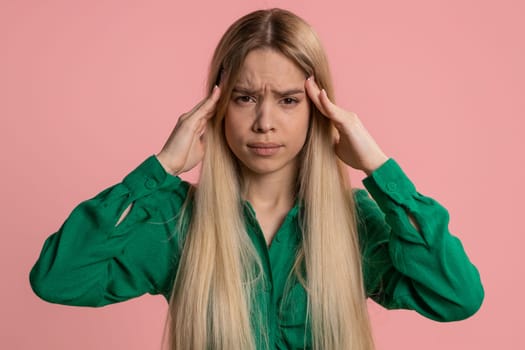 Sick ill caucasian teen young woman rubbing temples to cure headache problem, suffering from tension, migaine, stress, grimacing in pain, high blood pressure isolated alone on pink wall background