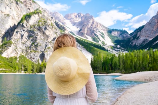 Young woman in white dress and hat enjoying the picturesque lake Braies and Dolomites Alps, Italy.