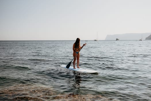 Close up shot of happy young caucasian woman looking at camera and smiling. Cute woman portrait in bikini posing on a volcanic rock high above the sea