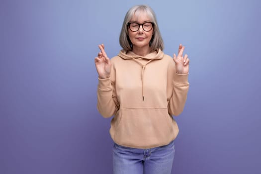 middle aged business woman with gray hair crossed her arms and prays on studio background with copy space.
