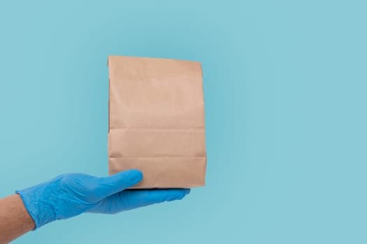 Close up hand in medical glove and holding food paper bag on white background ( Isolated background). Concept of Ordering food online and delivery service.