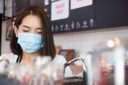 Asian barista women wearing face masks to prevent contagious diseases and serve customers in the coffee shop. The concept of prevention from COVID 19