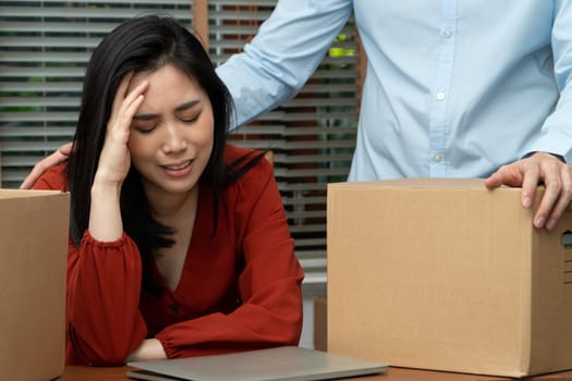Sad Asian woman Packing belongings in a cardboard box and crying on the desk in the office After being layoff and unemployed. Concept of impact on the economic downturn And management of the failure