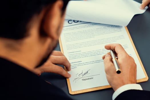 Closeup hand signing contract document with pen, sealing business deal with signature. Businesspeople finalizing business agreement by writing down signature on contract paper. Fervent