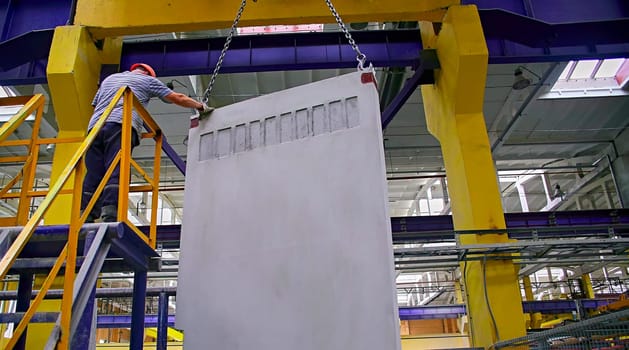 A builder installs a concrete floor slab panel at a construction site. Installation of a concrete floor slab for a multi-storey building.