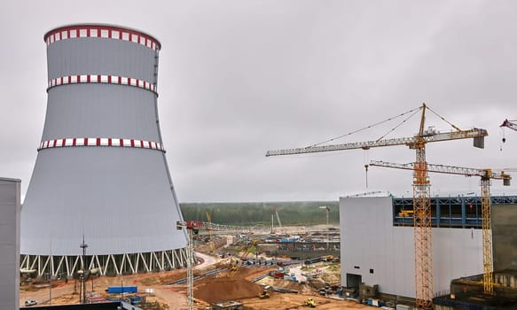 Construction of a nuclear power plant. Tower cranes on the background of the cooling tower.