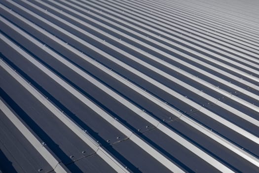 Roof slope covered with new weatherproof trapezoidal sheet. Large roof area on sports hall.