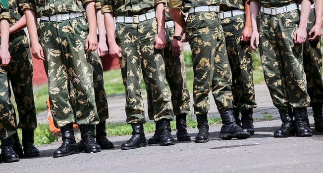 Russian military detachment of border guards stands on the street. Hands and boots close-up.