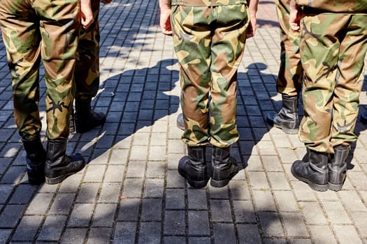 Russian military detachment of border guards stands on the street. Hands and boots close-up.
