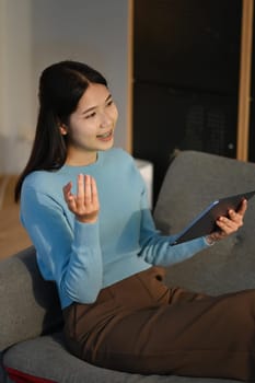 Shot of young woman using her digital tablet while sitting on sofa at home. High quality photo