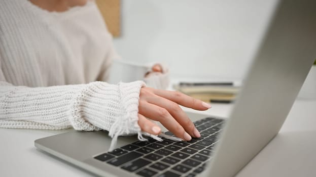 Close up view of young woman hand typing on keyboard of laptop. Freelance, distance, education, e-learning concept.