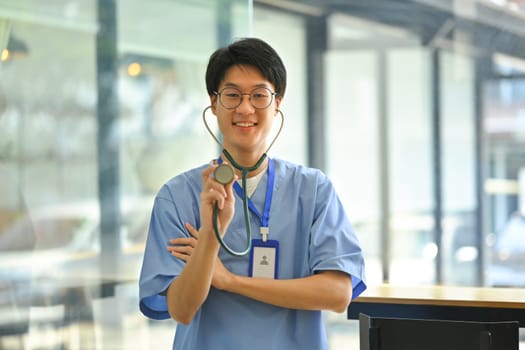 Portrait of doctor in blue uniform holding stethoscope in hand smiling to camera. Healthcare and medical concept.