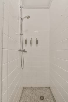 a walk in shower with white tiles on the walls and floor, it appears to be used as a bathtub