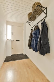 a hallway with coat racks and coats hanging on the wall next to an entry way in a door is behind it