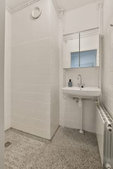a bathroom that is white and has black specs on the floor, with a sink and mirror in it