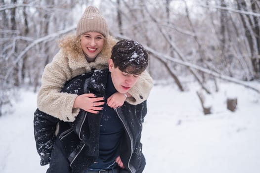 A young couple walks in the park in winter. Guy and girl hugging outdoors