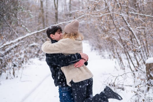 A young couple walks in the park in winter. Guy and girl hugging outdoors