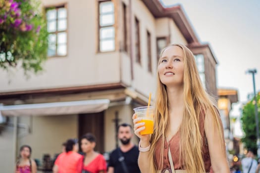 Happy woman tourist with fresh juice on background of old street of Antalya. female tourist traveler discover interesting places and popular attractions and walks in the old city Kalechi of Antalya, Turkey. Turkiye.