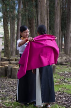 young otavalo native dresses her indigenous friend for a traditional facelift at a wedding. High quality photo