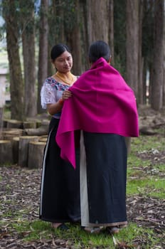 indigenous woman dresses her daughter with a fuchsia cloak on her wedding day. High quality photo
