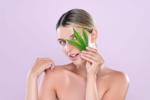 Alluring beautiful woman model portrait holding green leaf as concept for cannabis skincare cosmetic product for perfect skin freshness treatment in isolated pink background.