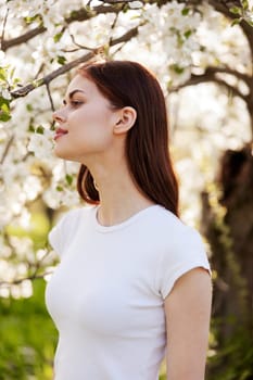portrait of a lovely, beautiful woman against the backdrop of a flowering tree in a white T-shirt. High quality photo