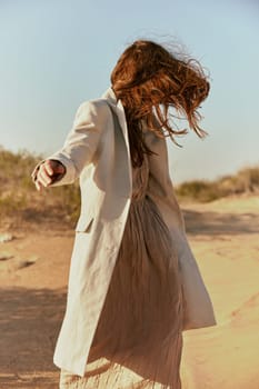 stylish woman with long red hair covering her face posing in nature. High quality photo