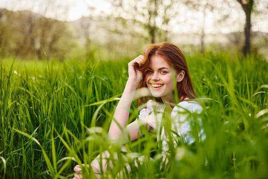 a young woman sitting resting in the tall grass straightening her hair. High quality photo