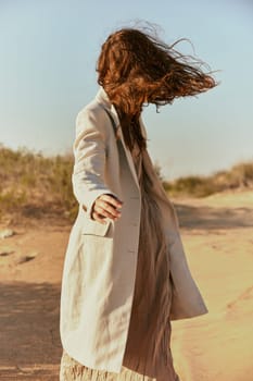 stylish woman with long red hair covering her face posing in nature. High quality photo