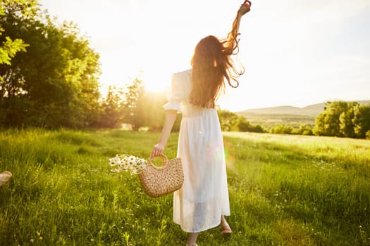 a girl in a long light dress stands in a field during sunset with her back to the camera. Full length photo. High quality photo