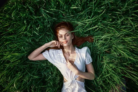 an elegant woman in a light dress lies in the grass and enjoys life. High quality photo