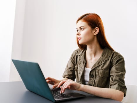 pensive redhead woman sitting at laptop while working in office. High quality photo