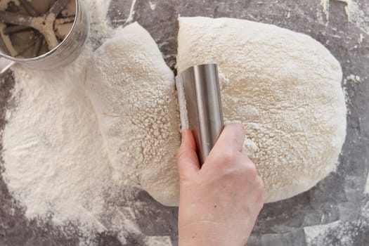 A woman's hand cuts the dough into pieces with a knife. Cooking bread, ciabatta.