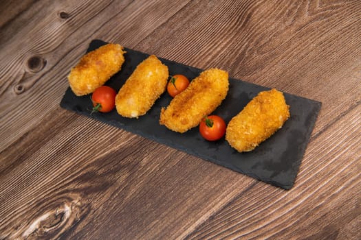 Homemade traditional Spanish croquettes or croquetas on a black plate with fork, Tapas food, High quality photo