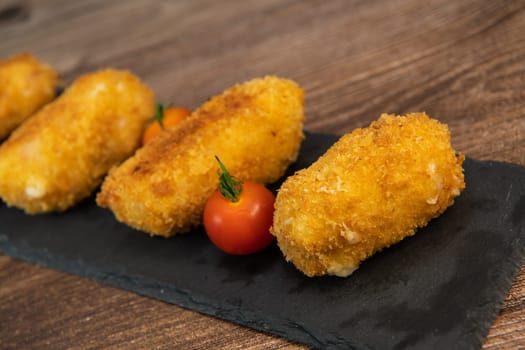 Homemade traditional Spanish croquettes or croquetas on a black plate with fork, Tapas food, High quality photo
